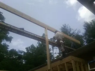 Carpenter setting a ridge beam over a new addition frame — Ice Dam Removal by Roofing Brothers in Brazil