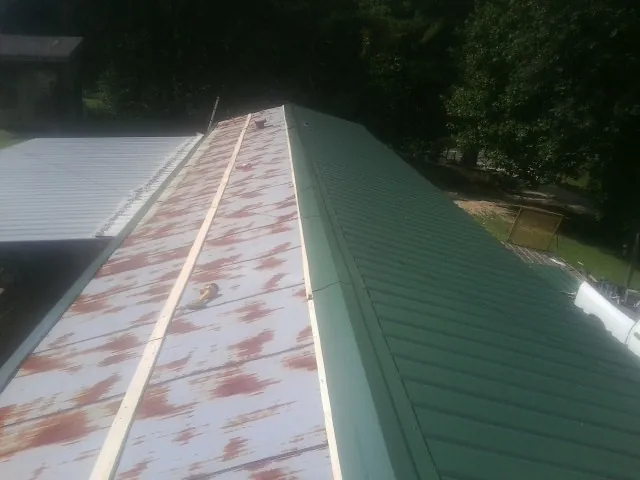 Old rusted panels beside newly installed green metal roofing — Wind Damage Roof Repair by Roofing Brothers in Brazil