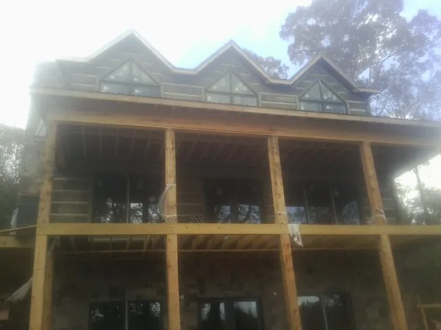 Dormers and porch framing on a large log home under construction — Roof Coating work by our crew in Brazil