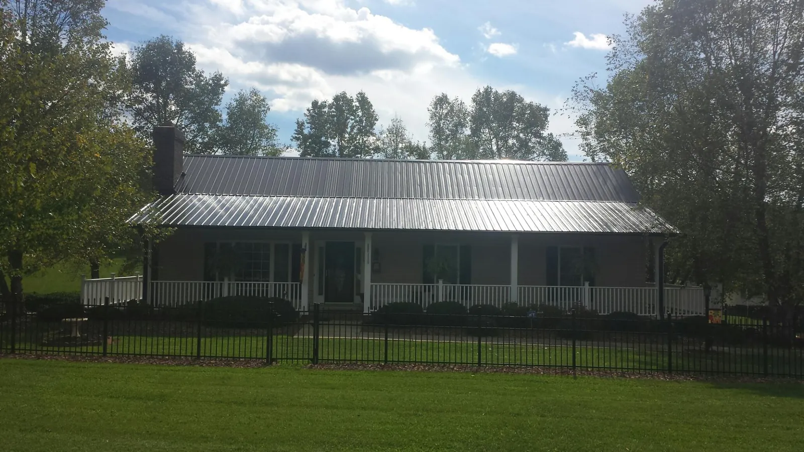 Gray metal roof on a brick ranch with a full width front porch — Gutter Guard Installation work by our crew in Brazil