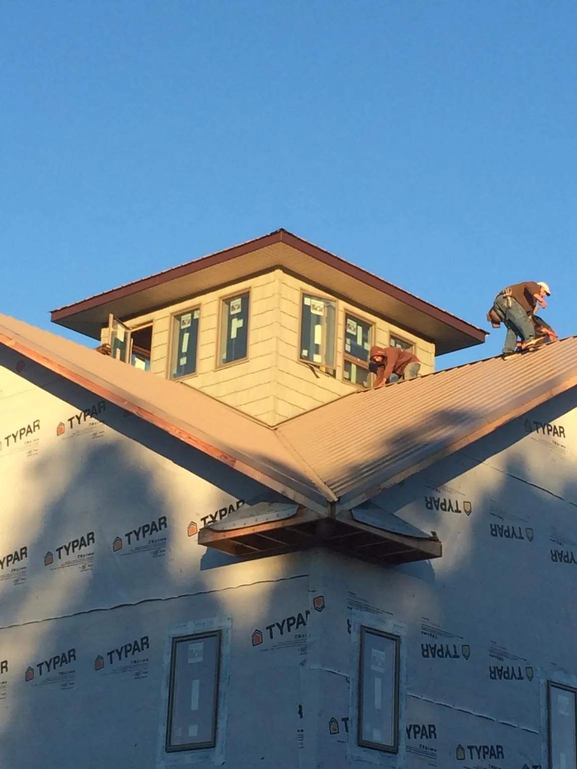 Roofers working around a rooftop cupola on a new metal roof at sunset — Roof Waterproofing in Brazil by Roofing Brothers